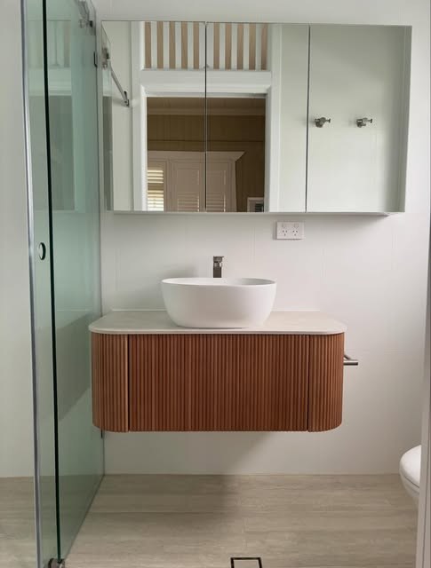 Fluted timber vanity with a round basin and mirrored shaving cabinet